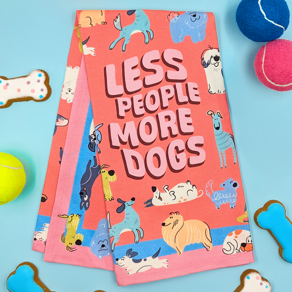 Tea Towel titled 'Less People More Dogs' surrounded by dog-themed cookies and toys on a blue background