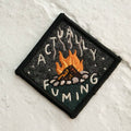 Embroidered patch with a campfire design and text on a textured white background