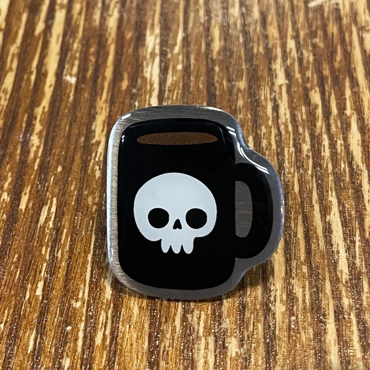 Black kettlebell-shaped object with a white skull design on a wooden surface, branded 'Rapscallion'.