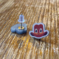 Cartoon character cowboy hat earrings on a wooden surface with 'RAPSCALLION' branding.